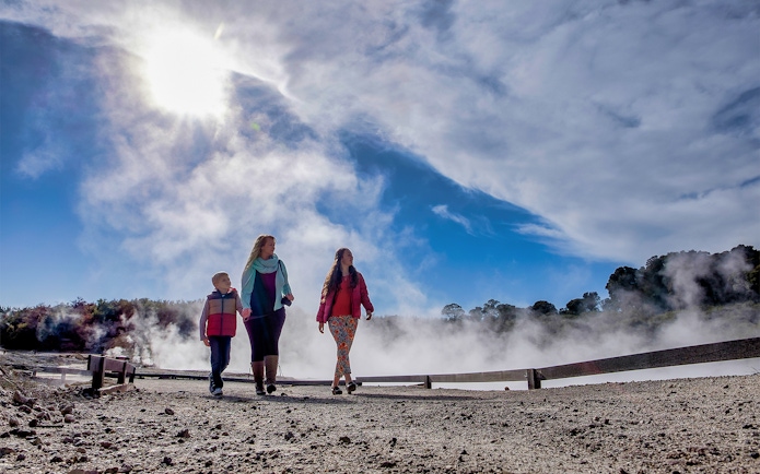 Visitors walking through geothermal steam at Hell's Gate, New Zealand.