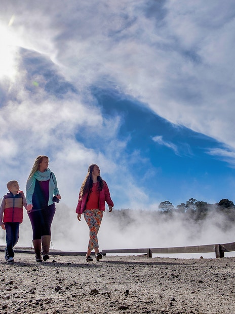 Visitors walking through geothermal steam at Hell's Gate, New Zealand.