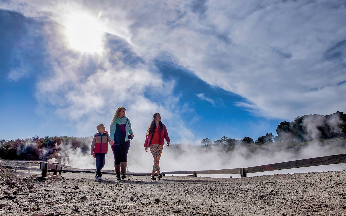 Visitors walking through geothermal steam at Hell's Gate, New Zealand.