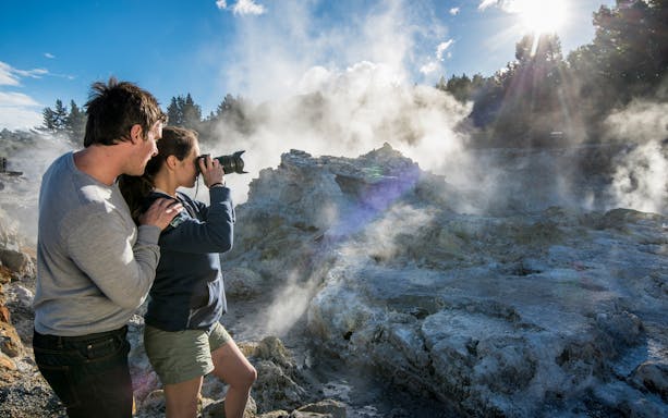 Visitors photographing geothermal steam at Hell's Gate Thermal Experience, New Zealand.