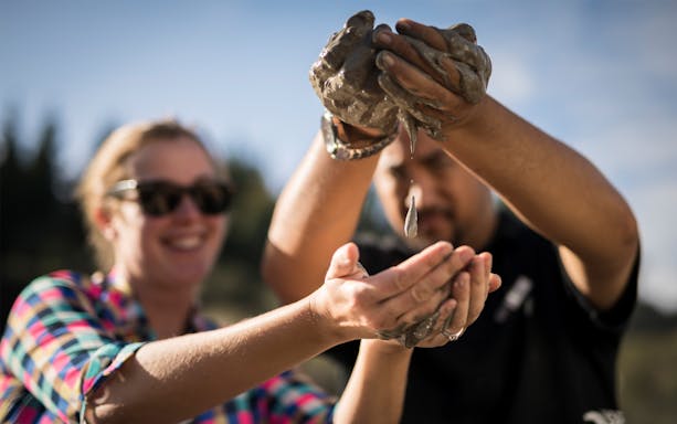 Hands holding and dripping mud at Hell's Gate Thermal Experience.