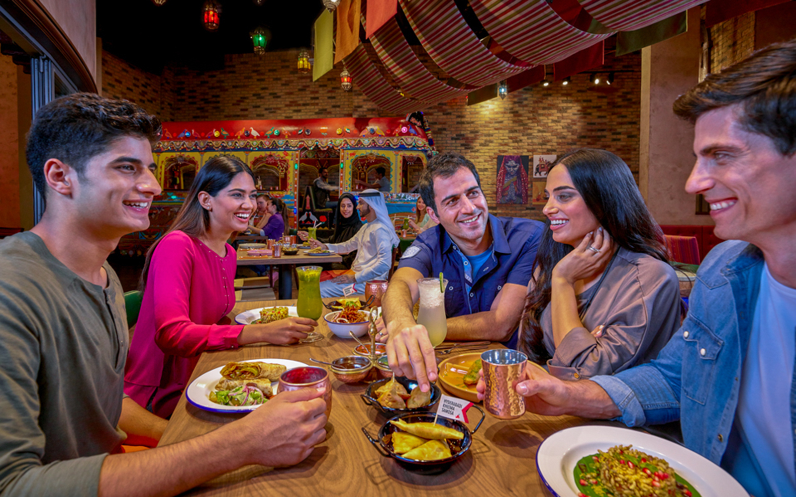 Group dining at a themed restaurant in Dubai, enjoying diverse dishes and drinks.