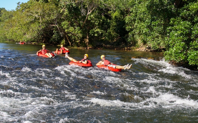 People enjoying river tubing on a scenic waterway surrounded by lush greenery.