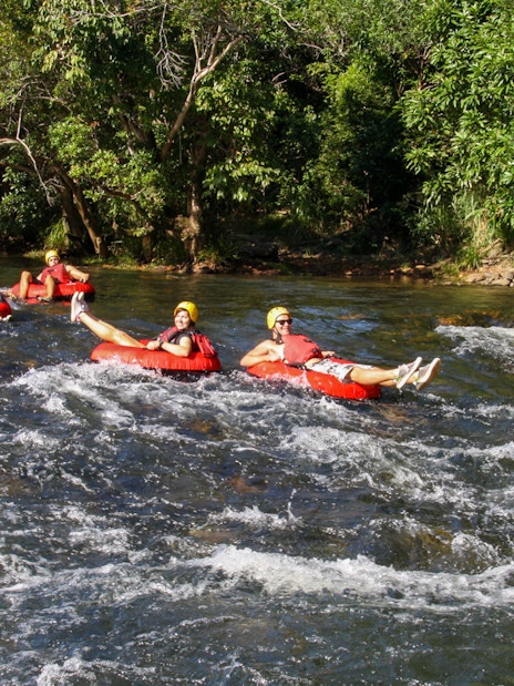 People enjoying river tubing on a scenic waterway surrounded by lush greenery.