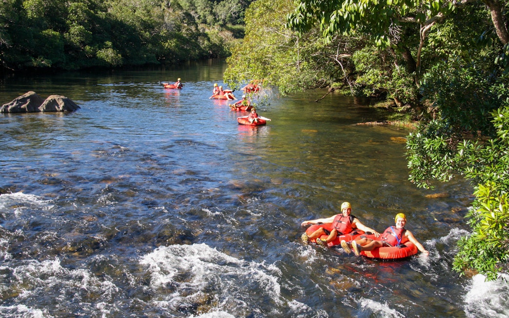 People enjoying river tubing through a scenic forested area.