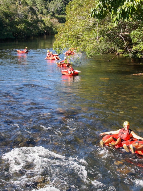 People enjoying river tubing through a scenic forested area.