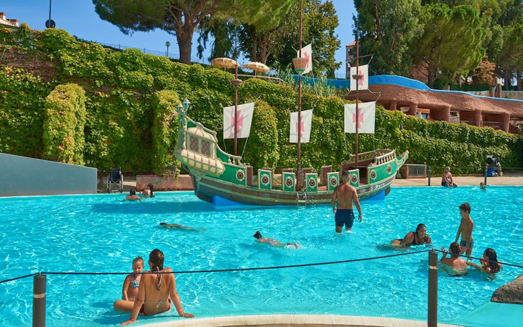 Visitors enjoying the pool near a pirate ship at Caravelle Aquapark.