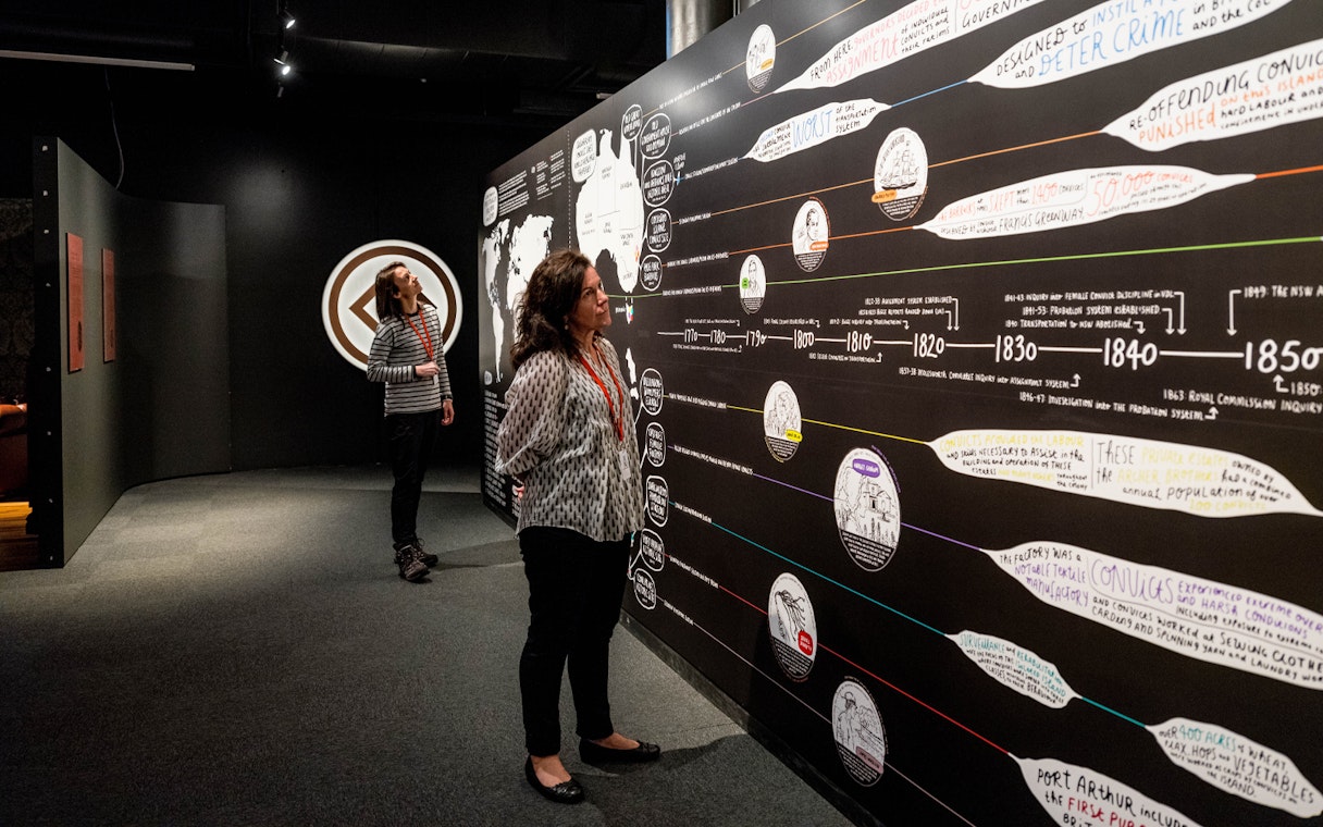 Visitors examining historical timeline at Port Arthur Historic Site exhibit.