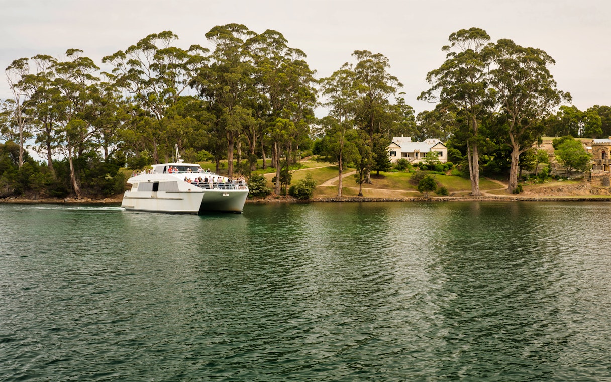 Ferry approaching Port Arthur Historic Site, Tasmania, surrounded by trees and water.