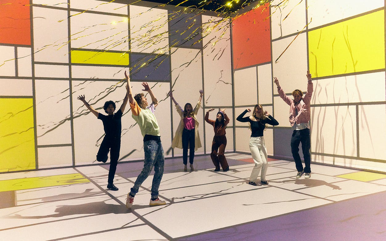 Group enjoying interactive audiovisual experience with colorful geometric projections.