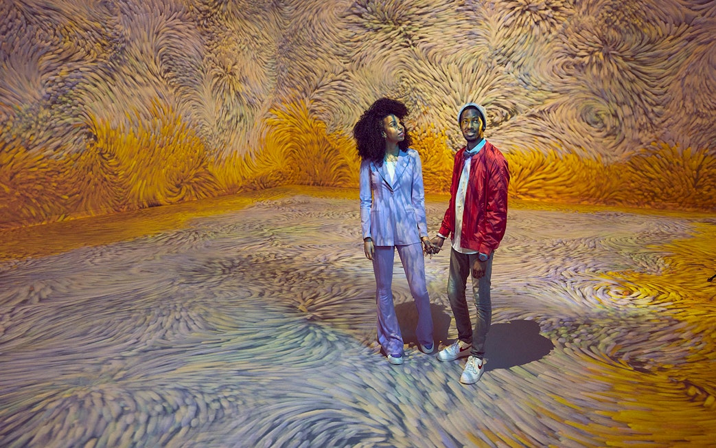 Couple enjoying immersive audiovisual art installation with swirling patterns.