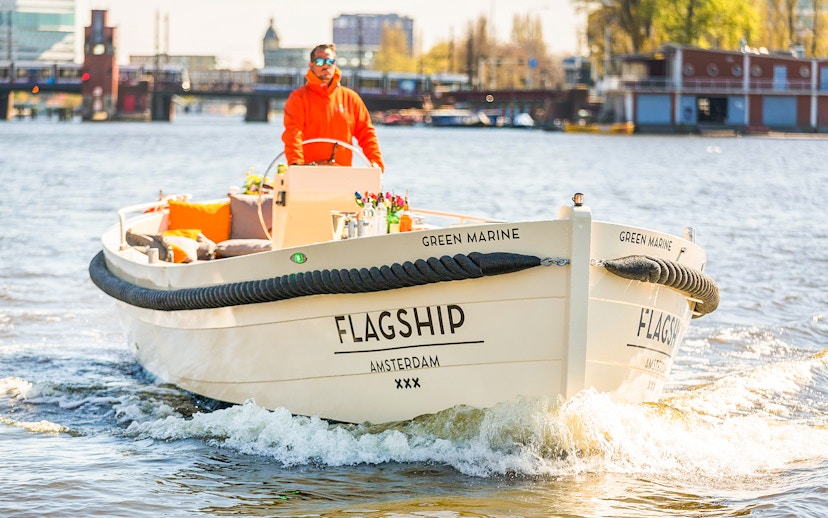 Open boat cruising on Amsterdam canal with drinks on deck.