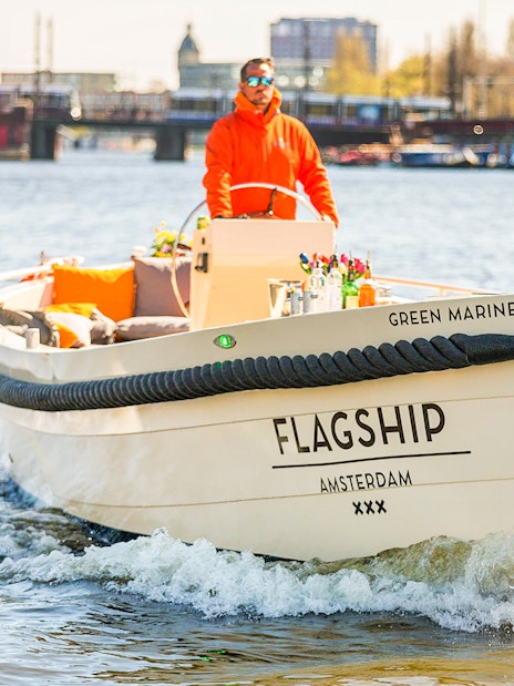 Open boat cruising on Amsterdam canal with drinks on deck.