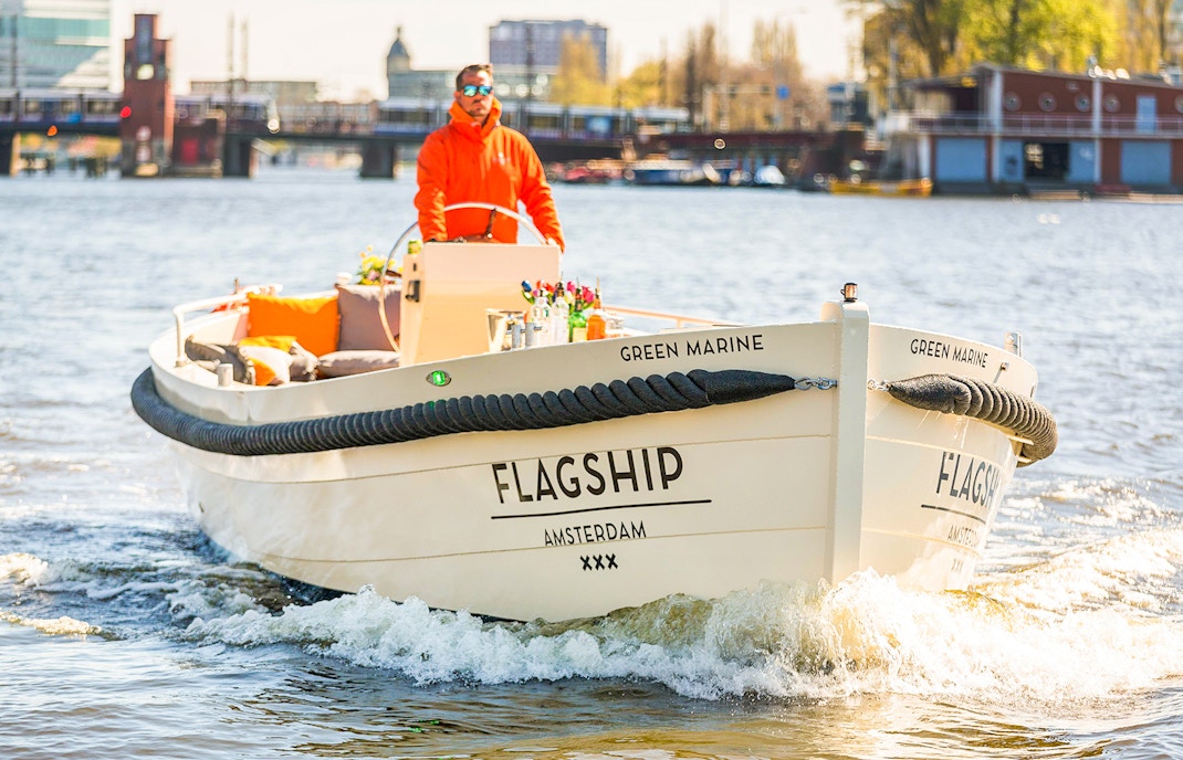 Open boat cruising on Amsterdam canal with drinks on deck.