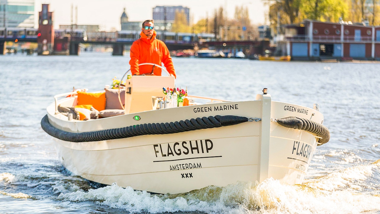 Open boat cruising on Amsterdam canal with drinks on deck.