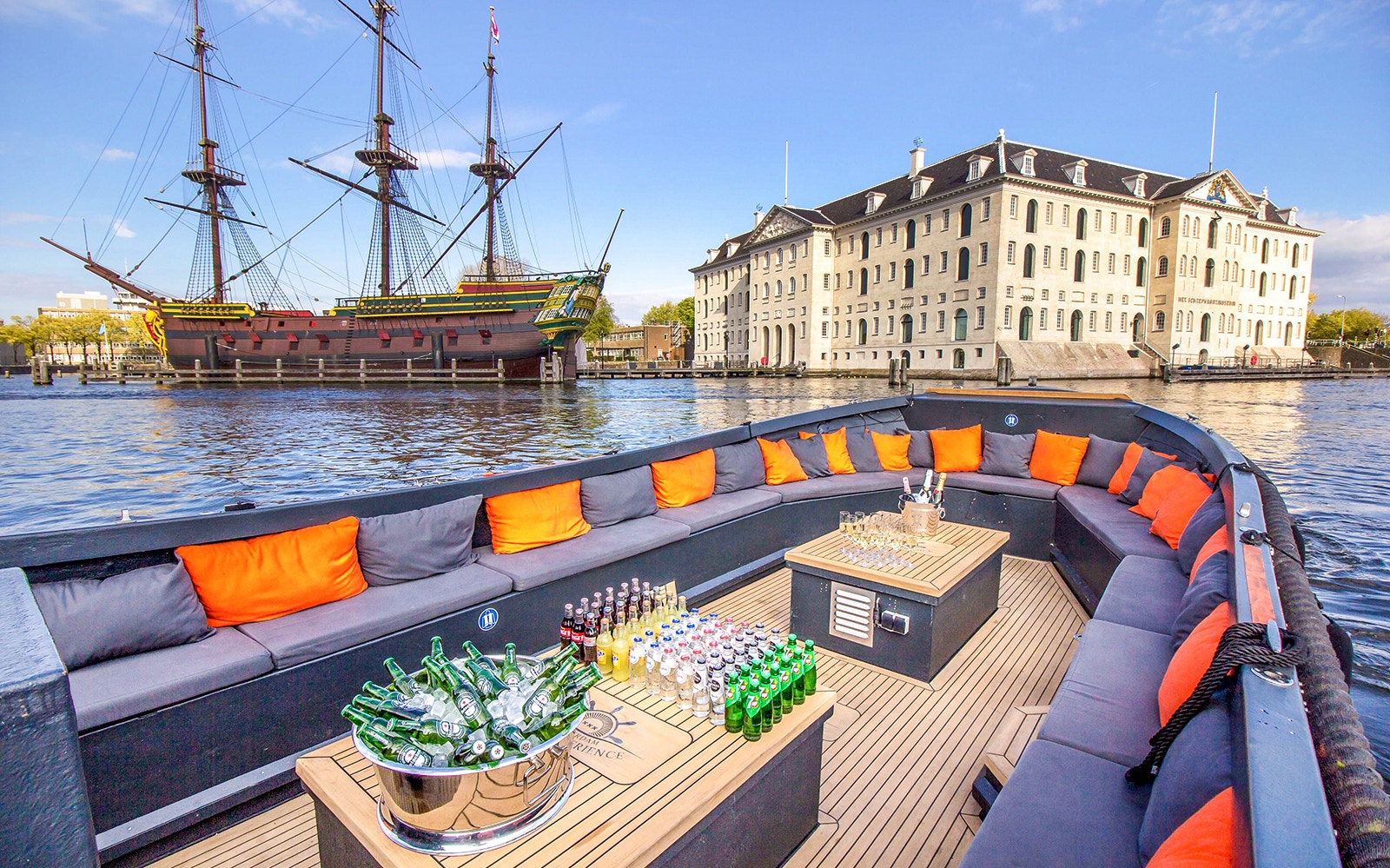 Amsterdam canal cruise boat with passengers enjoying drinks near Anne Frank House.