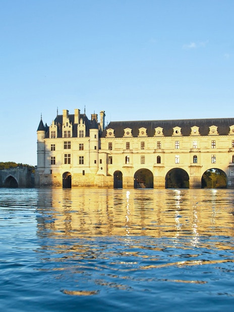 Chenonceau Castle reflecting on the Loire River at sunset.