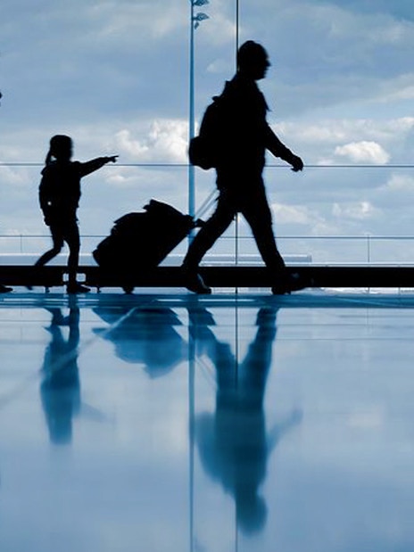 Family with luggage walking through Bucharest OTP Airport terminal.