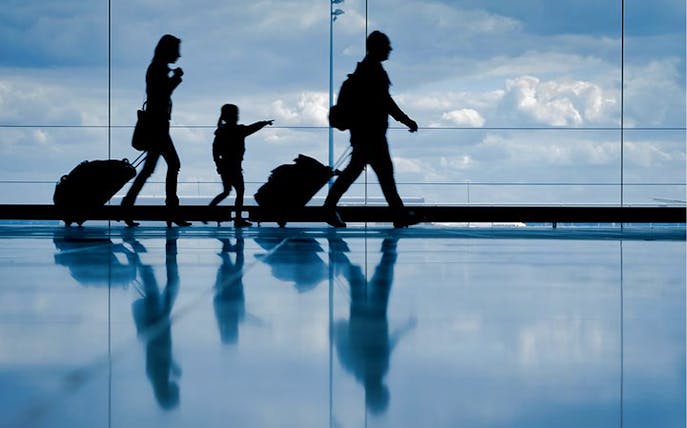 Family with luggage walking through Bucharest OTP Airport terminal.