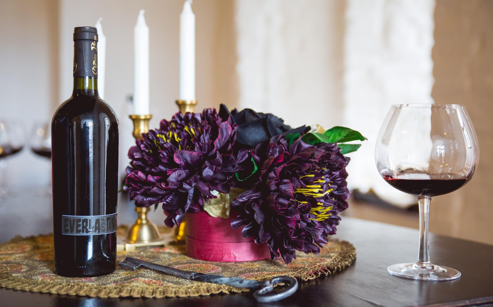 Wine bottle and glass with flowers on a table, Bucharest Dracula's Castle tour.