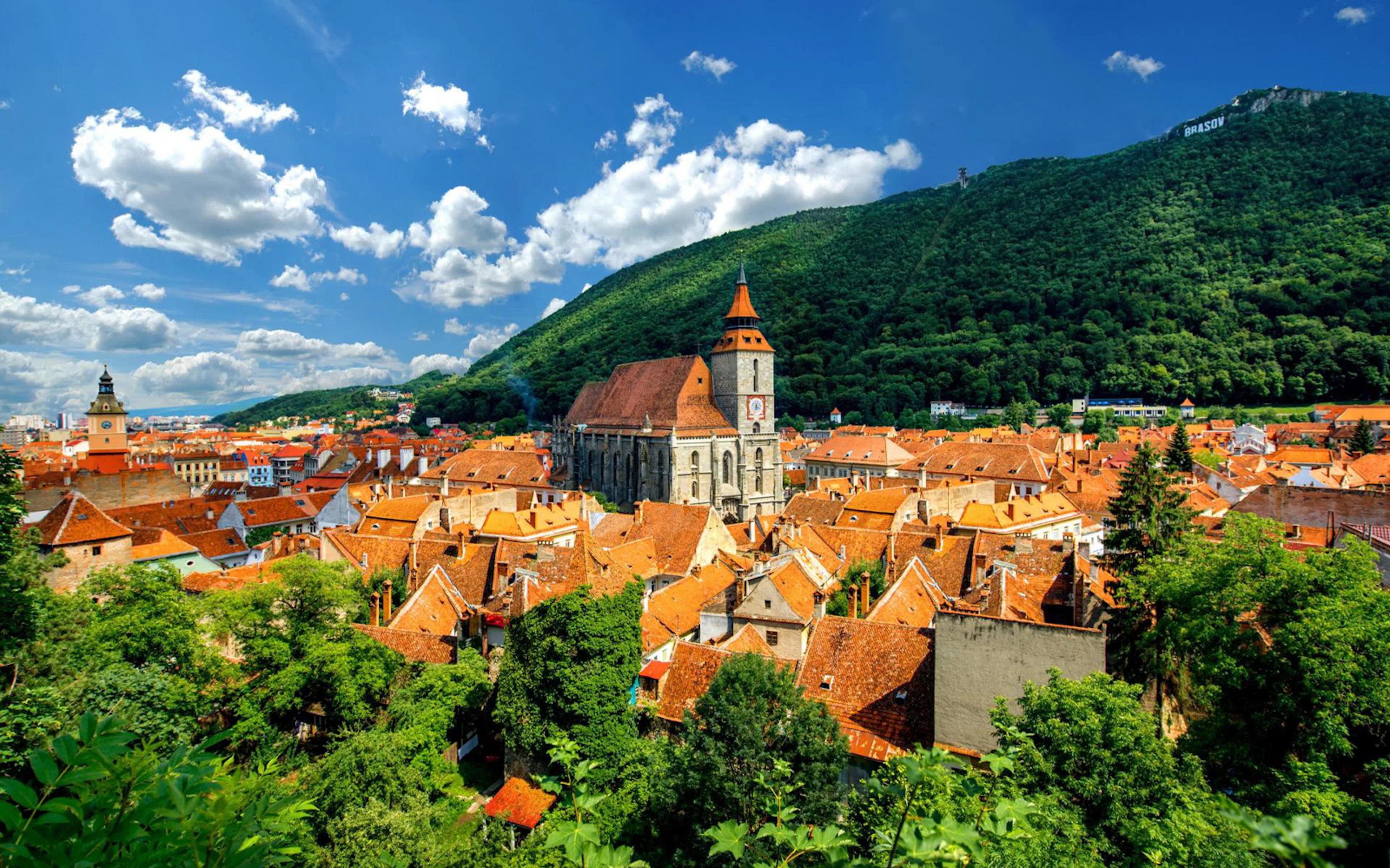 Brasov cityscape with Black Church and Carpathian Mountains in the background.