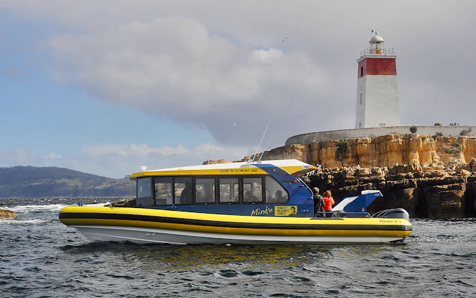 Boat cruising near Iron Pot Lighthouse, Tasmania.