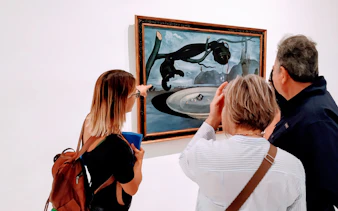 Guide explaining art piece to visitors at Reina Sofia Museum tour in Madrid.