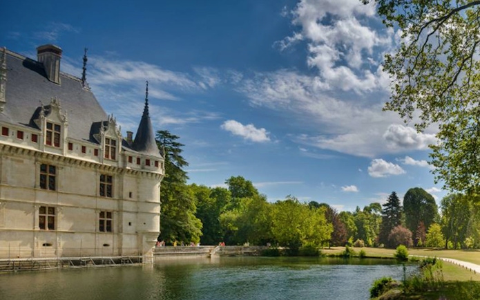 Azay le Rideau Castle by a river with lush greenery and a clear sky.