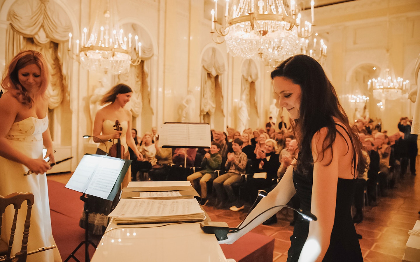 Musicians performing at Vienna Supreme Concerts in an elegant hall with chandeliers.