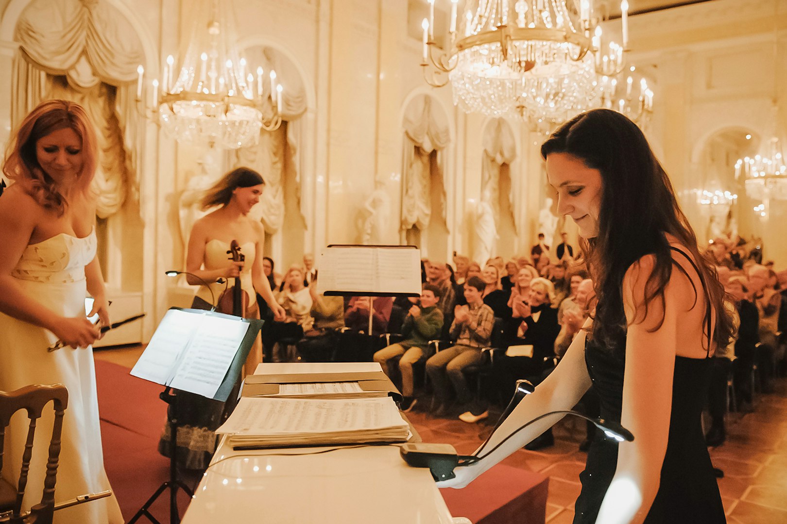 Musicians performing at Vienna Supreme Concerts in an elegant hall with chandeliers.