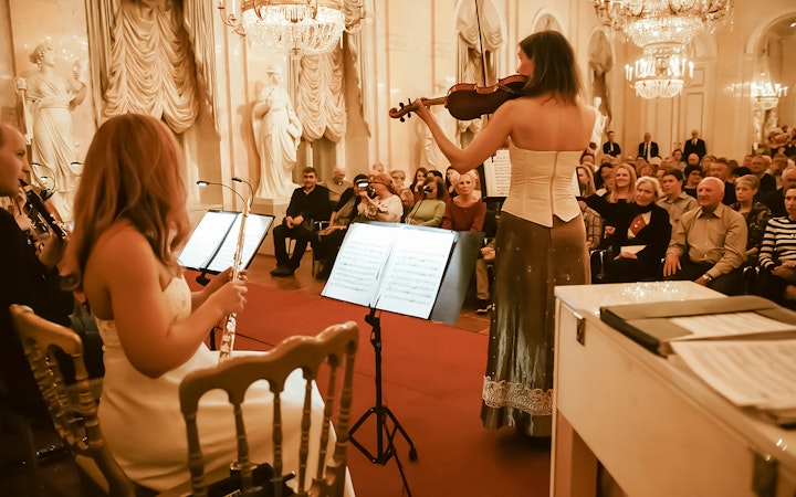 Musicians performing at Vienna Supreme Concerts with an audience in an elegant hall.