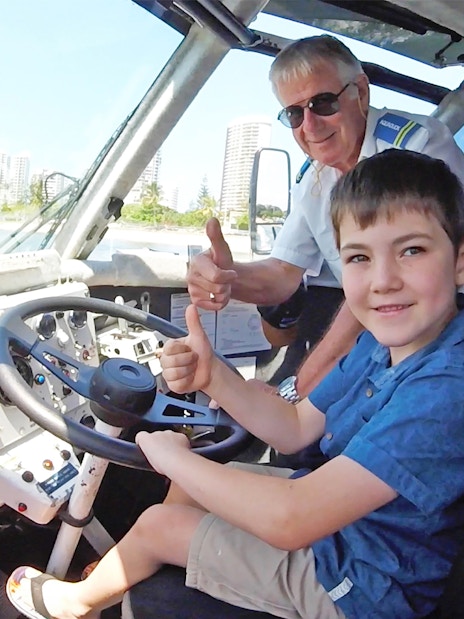 Child and guide giving thumbs up inside Aquaduck vehicle, Sunshine Coast skyline visible.