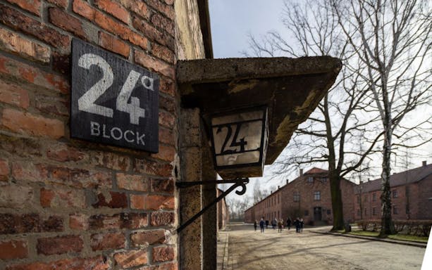 Block 24 sign at Auschwitz-Birkenau with visitors in the background, Krakow tour.