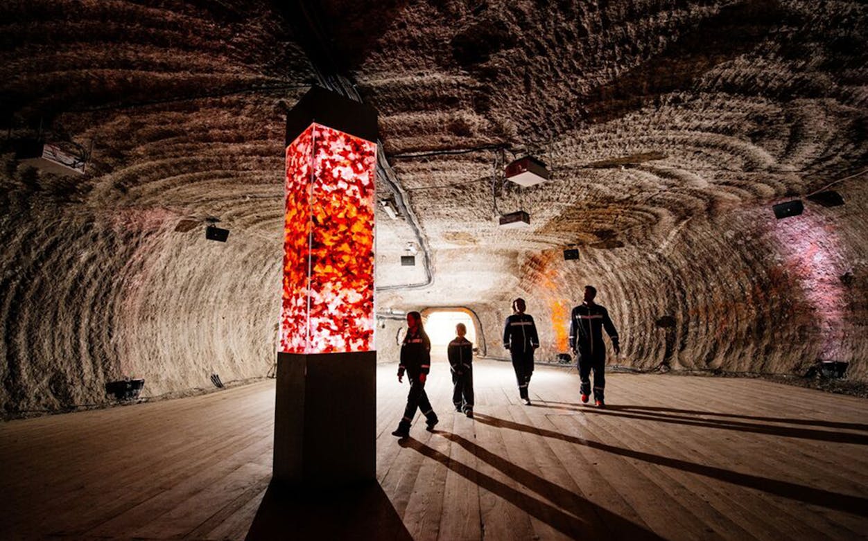 Visitors exploring Berchtesgaden Salt Mines in Salzburg with illuminated salt pillar.