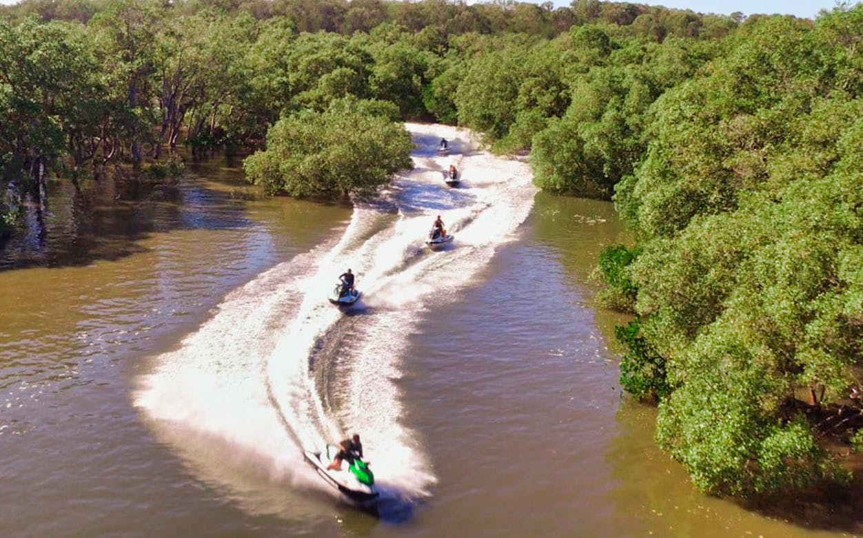 Jet skis navigating a winding river surrounded by lush greenery.