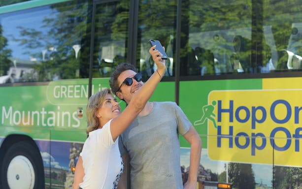 Couple taking selfie in front of Hop On Hop Off bus in Salzburg.