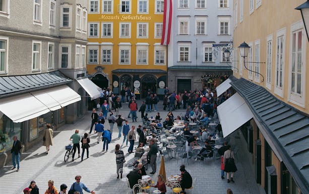 Mozart's Birthplace in Salzburg with tourists and outdoor cafes.