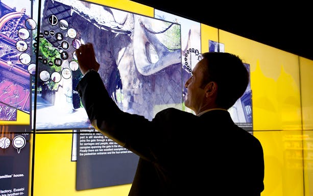 Man interacting with digital display at Gaudí 4D Experience in Barcelona.