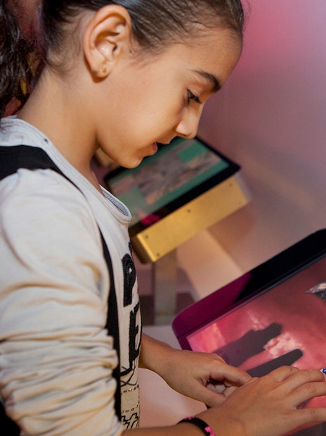 Child interacting with touchscreen at Gaudí 4D Experience exhibit.