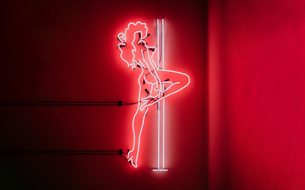 Neon silhouette of a dancer on a pole, part of the Tour de BonTon experience.