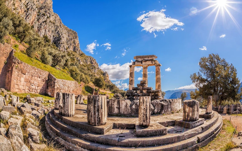 Ancient ruins of the Tholos of Delphi under a bright sky in Greece.