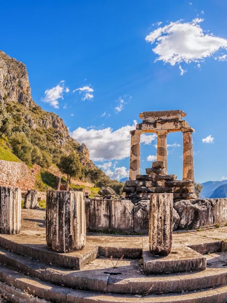 Ancient ruins of the Tholos of Delphi under a bright sky in Greece.