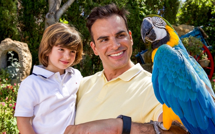 Father and son smiling with a parrot at Mundomar Marine Animal Park.