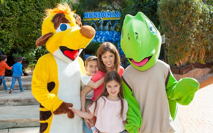 Family posing with animal mascots at Mundomar Marine Animal Park.