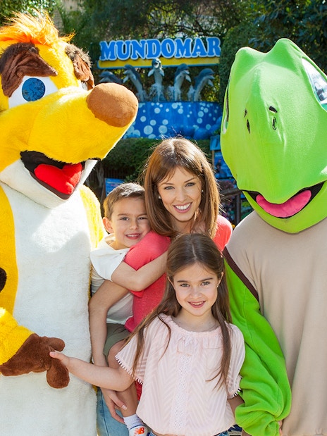 Family posing with animal mascots at Mundomar Marine Animal Park.