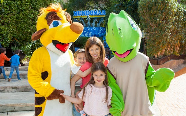 Family posing with animal mascots at Mundomar Marine Animal Park.
