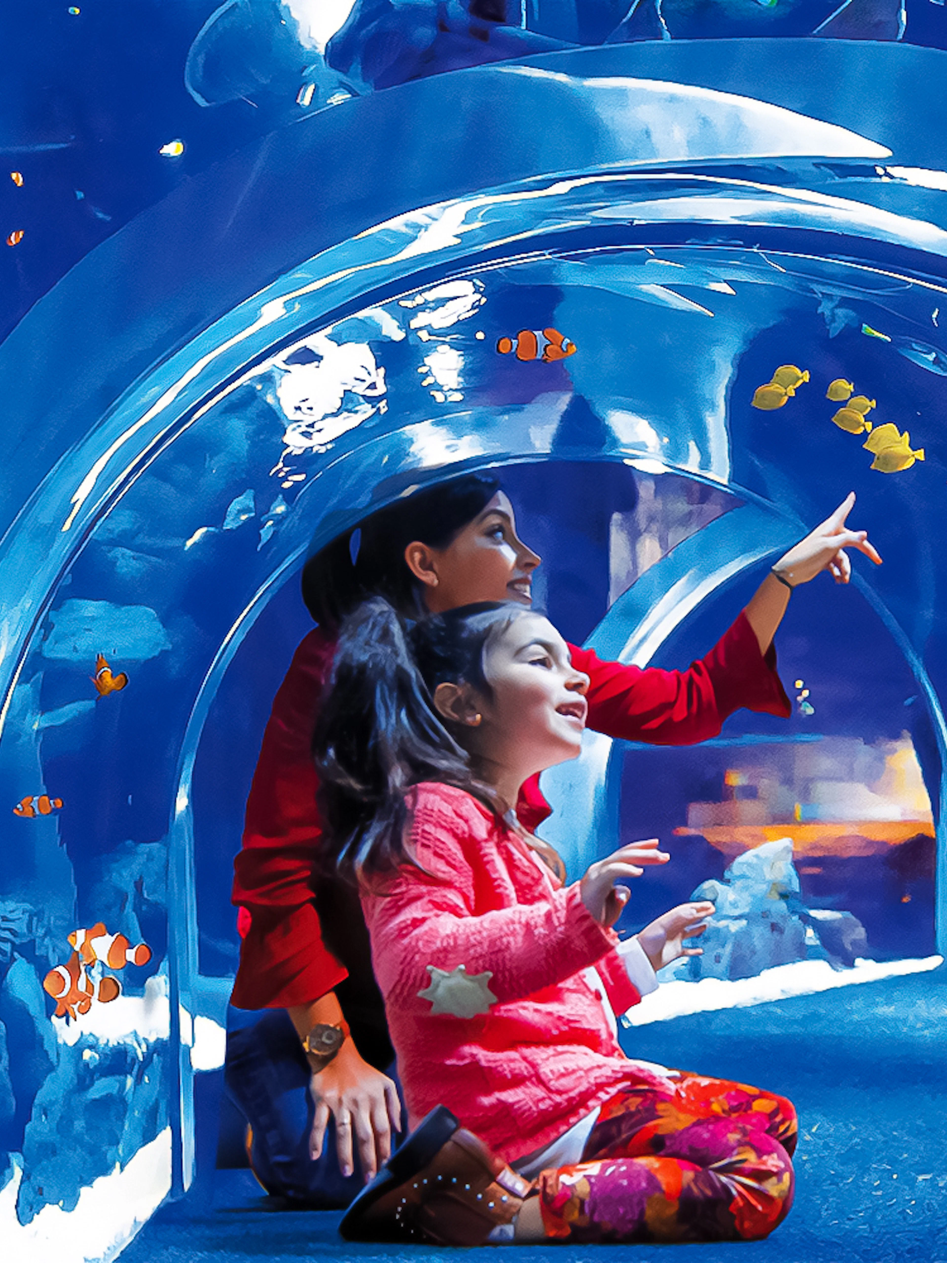 Visitors exploring underwater tunnel at Poema del Mar Aquarium, surrounded by colorful fish.