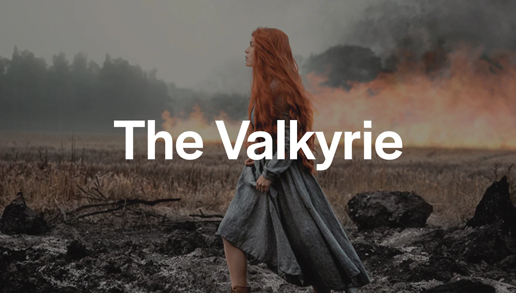 Red-haired woman in medieval dress walking through a smoky, burnt landscape.
