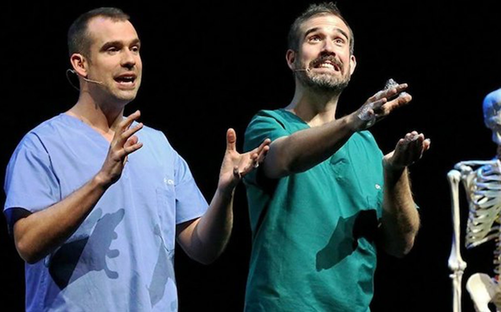 Two presenters in scrubs performing on stage with a skeleton for Operation Ouch Live.