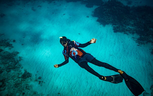 Snorkeler exploring vibrant coral reef during Dreamtime Dive & Snorkel Experience from Cairns.